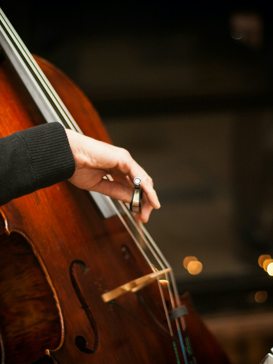 Close-up of a hand drawing a bow across the strings of a cello