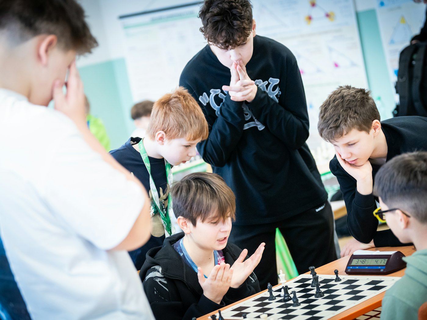 Pupils crowded round a chessboard, deep in thought over the next move