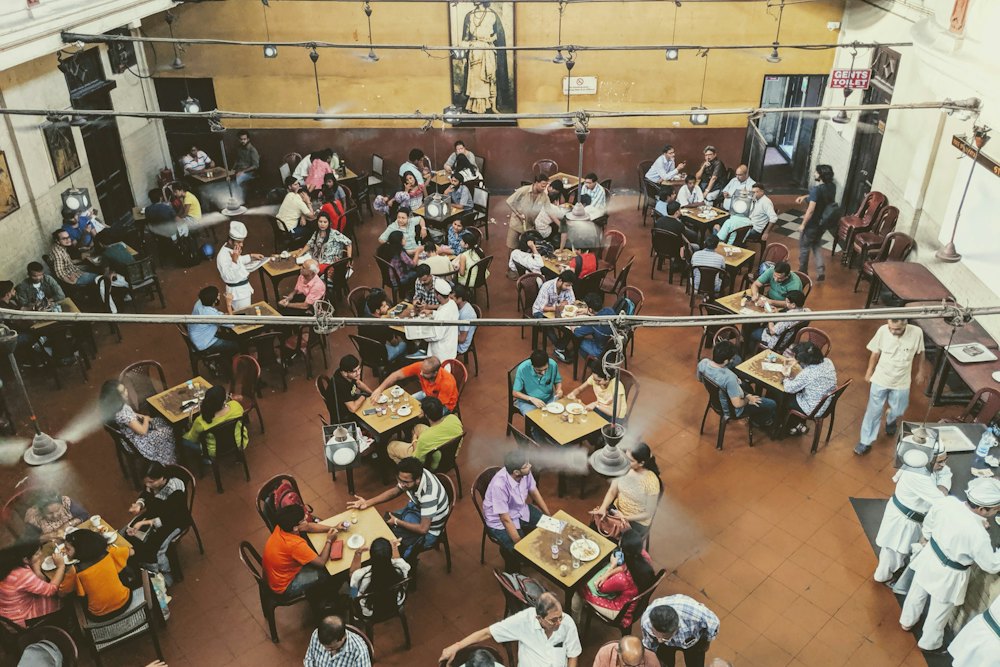 A busy dining hall seen from above, with groups eating at tables