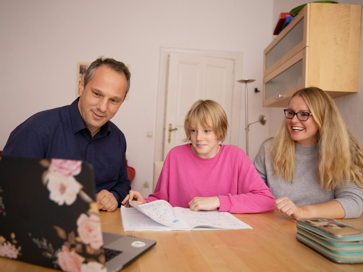 A parent and child talking with a member of staff around a table, all smiling
