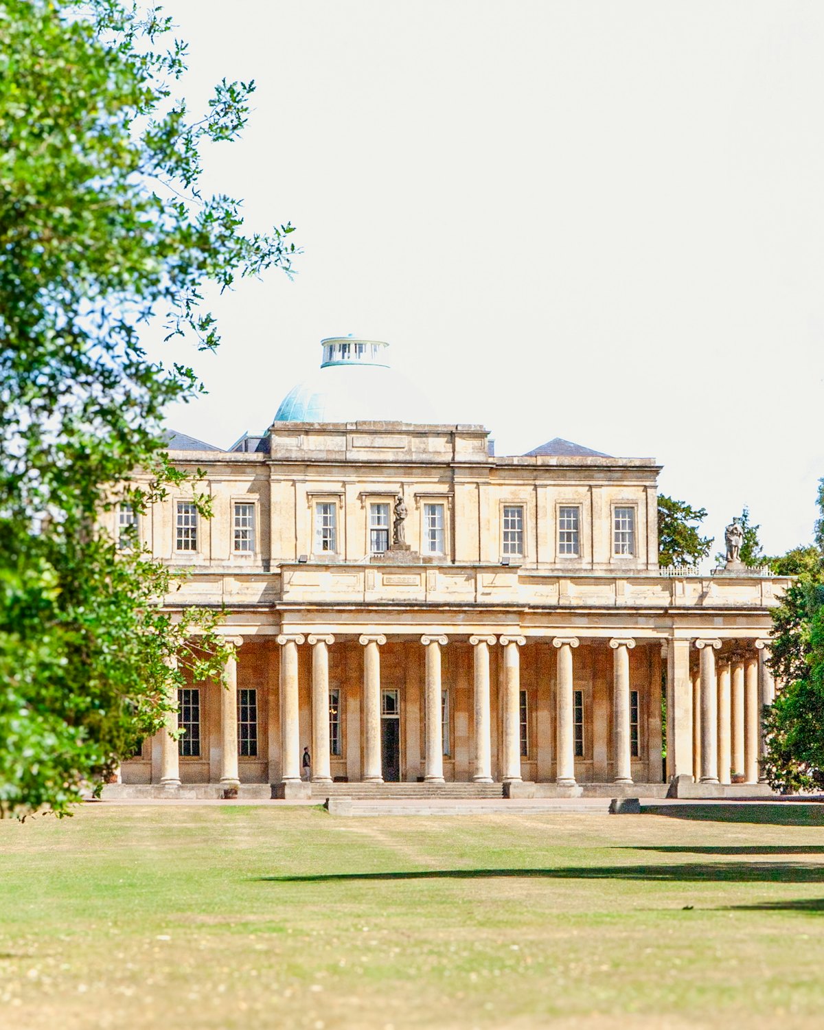 The colonnaded front of Pittville Pump Room, Cheltenham's Regency spa building, seen across its lawn
